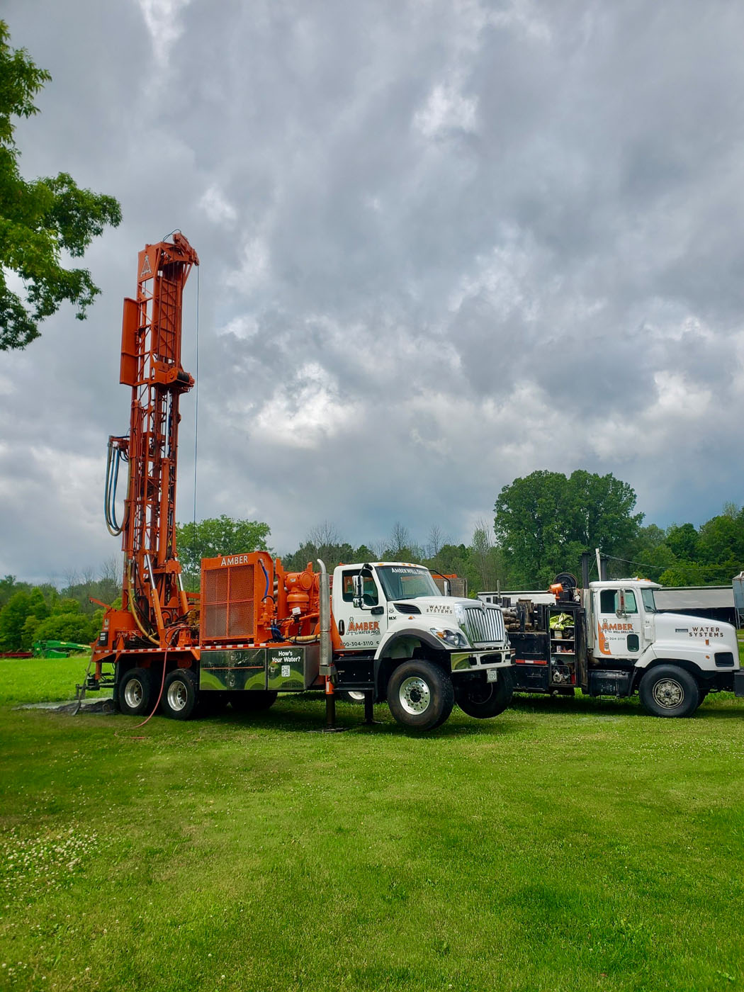 A Amber Water Pros well drilling truck in trees - call Amber Water Pros for Upstate NY & NE PA well and pump repair.