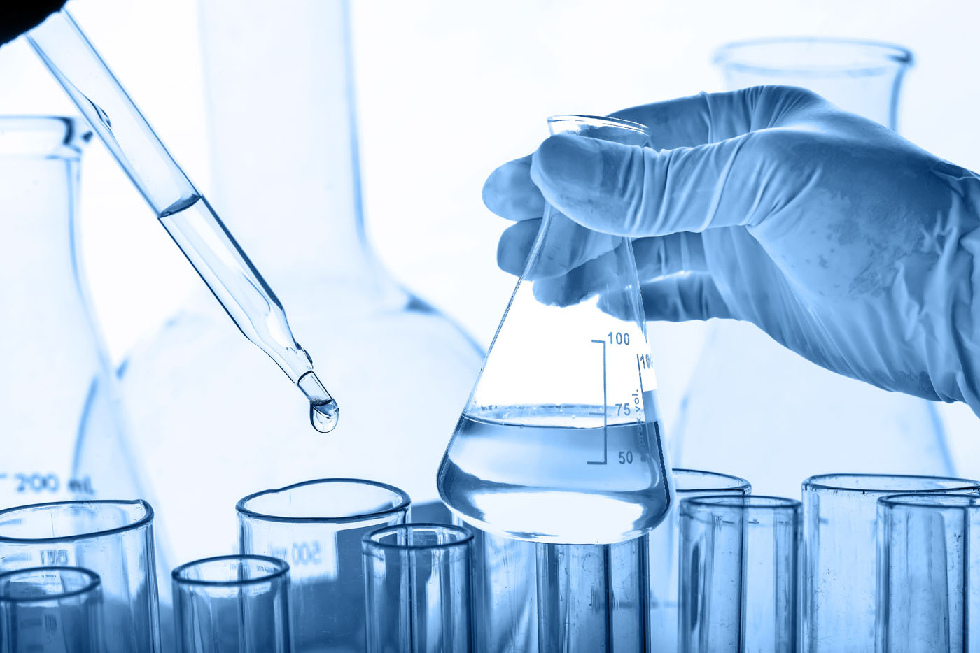 An image of a professional testing water quality with different viles and scientific equipment.